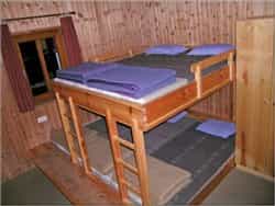 Wooden bunk beds with purple blankets inside a room with wood-paneled walls.