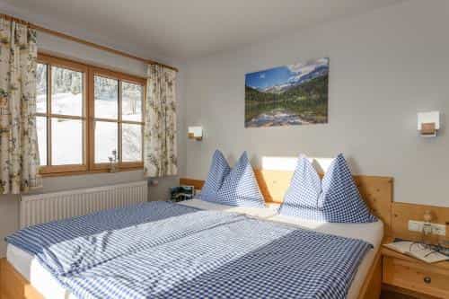 Bedroom with wooden bed, blue gingham bedding, and snowy view through window