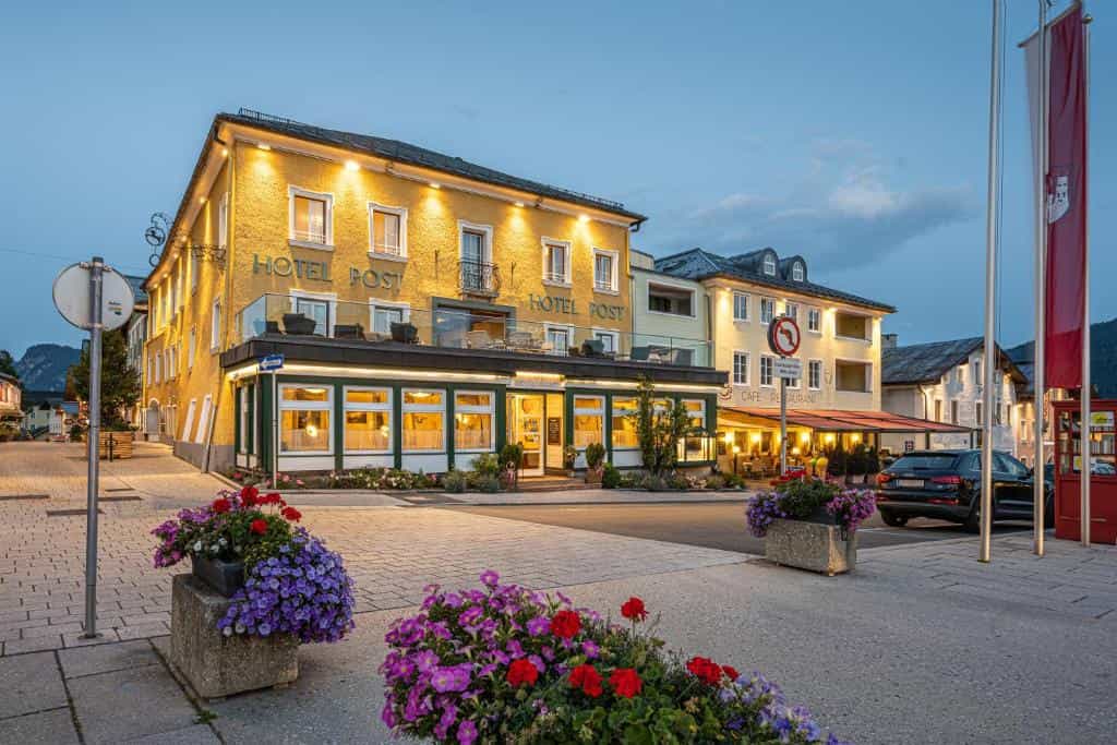Hotel Post building illuminated at dusk with flower planters in Radstadt.
