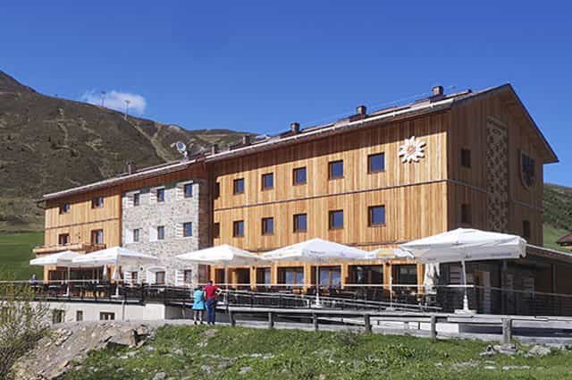 Dortmunder Hütte mountain lodge with wooden facade and outdoor terrace against green alpine slopes.