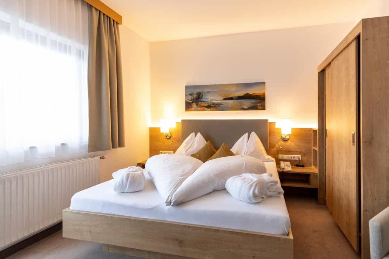 Hotel Turracherhof room with wooden bed, white linens, and landscape artwork above the headboard.