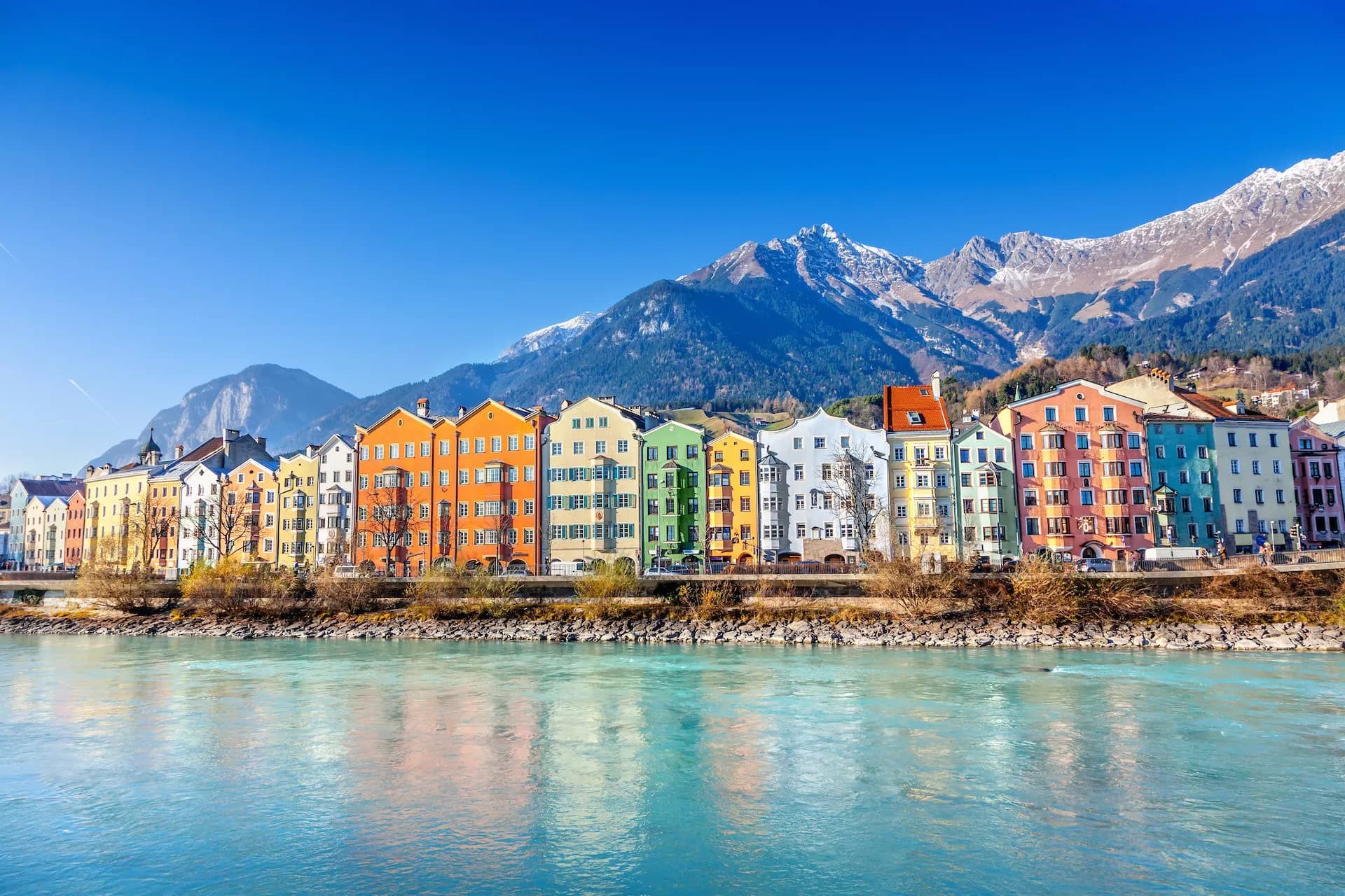 Colorful buildings along the river with snow-capped mountains in Innsbruck, Austria