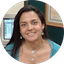 Woman smiling in a circular profile picture with a computer monitor visible in the background.