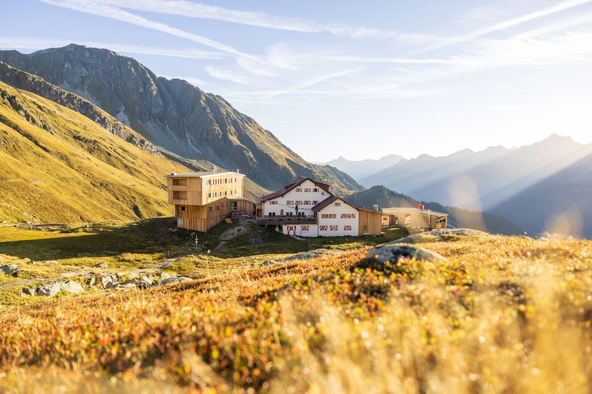 Neue Regensburger Hütte mountain hut nestled in the alpine landscape during a sunny day.