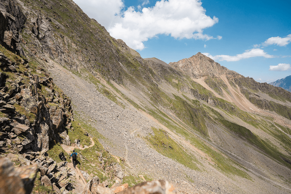 Hiker on a narrow mountain trail in the Stubai Alps.