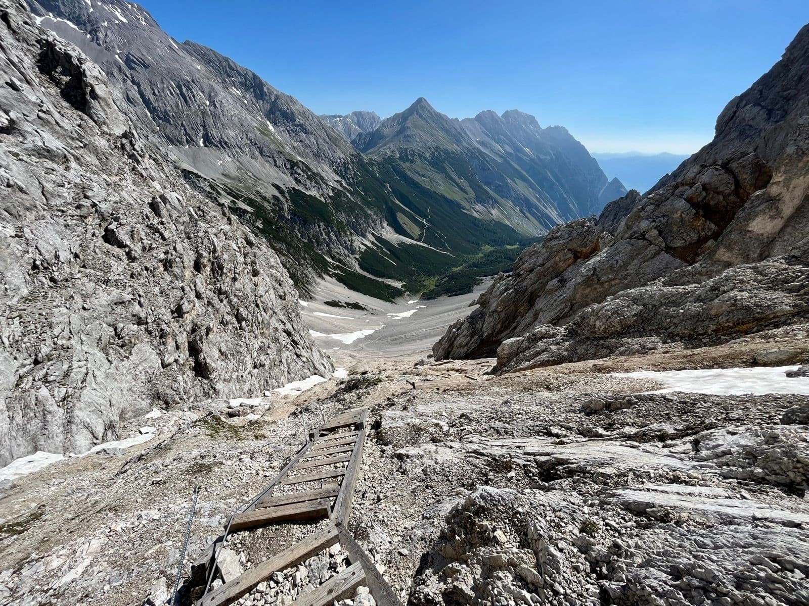 Wooden ladder on a steep, rocky hiking trail in the high alpine mountains.