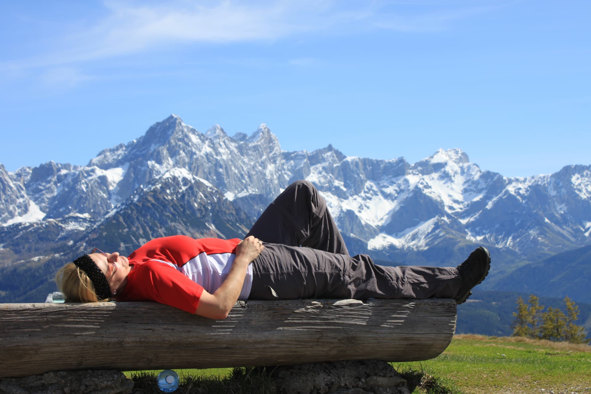 Woman resting on log with snow-capped Rossbrand mountains in background