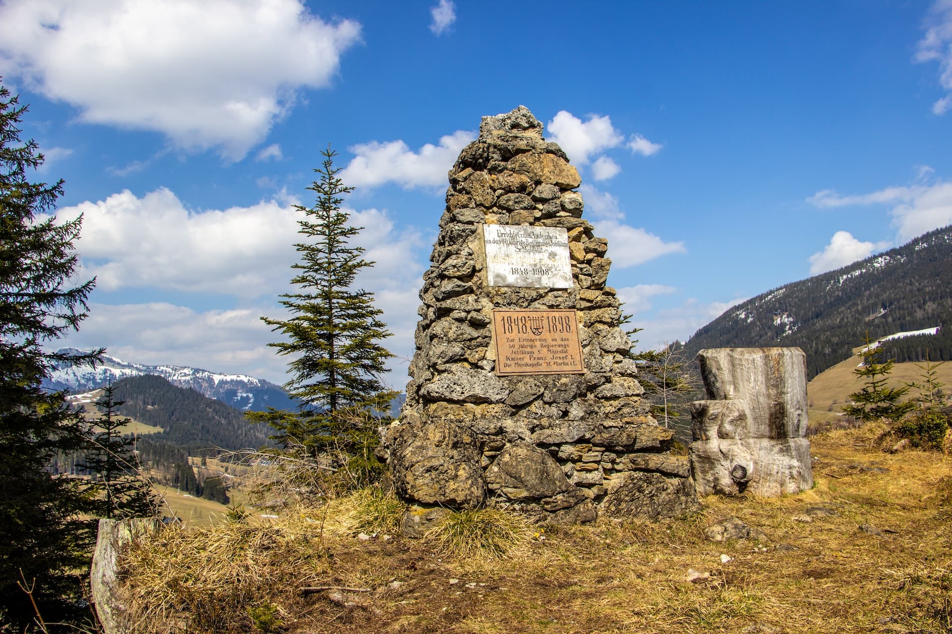 Stone memorial cairn with plaques on a grassy mountain slope in St. Martin im Tennengebirge.