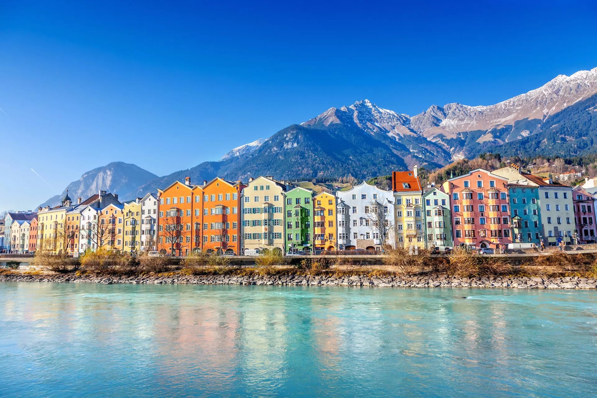 Colorful buildings along the river with snow-capped mountains in Innsbruck, Austria