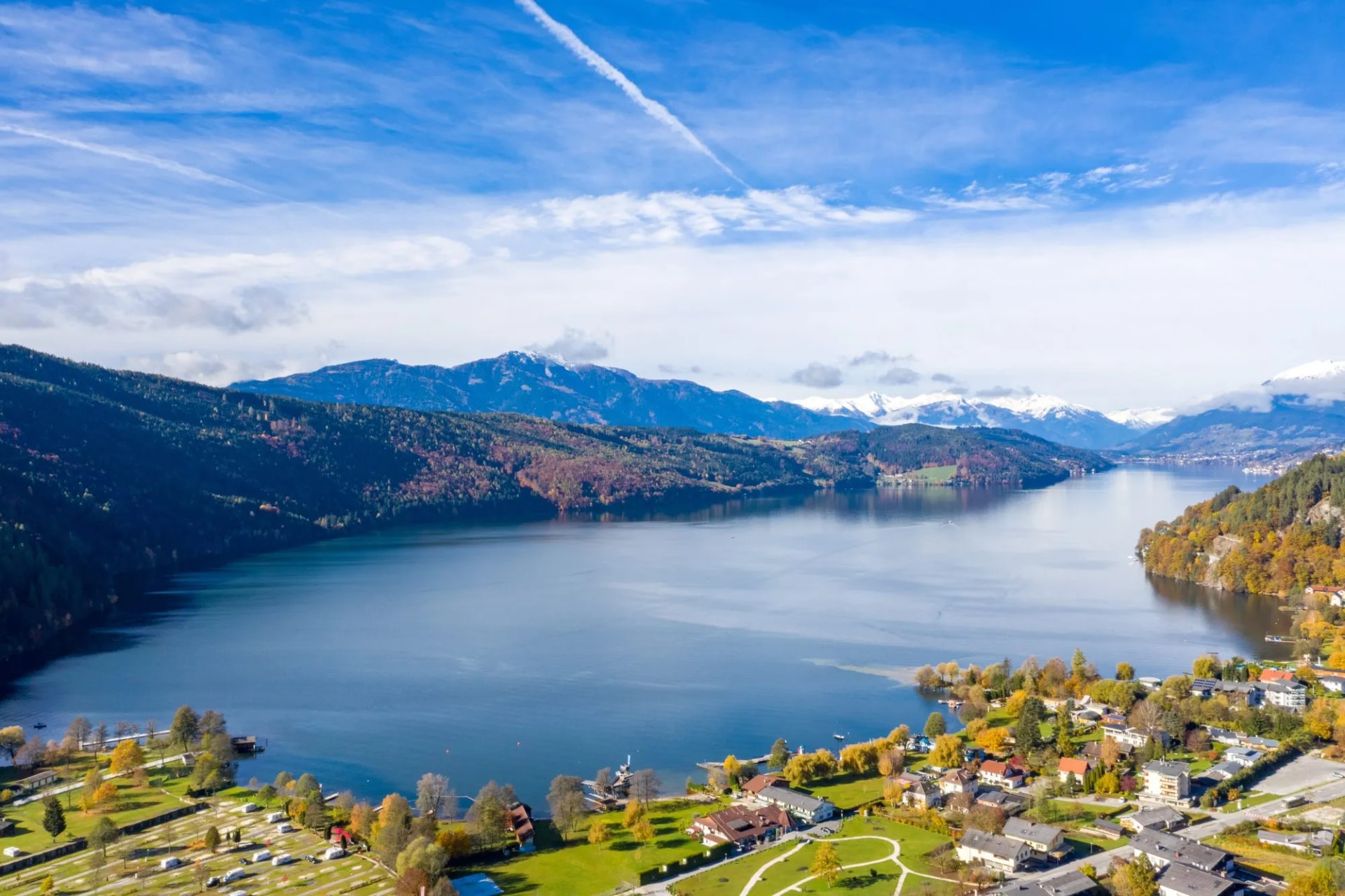 Lake Millstatter See in Carinthia with autumn foliage and snow-capped mountains.