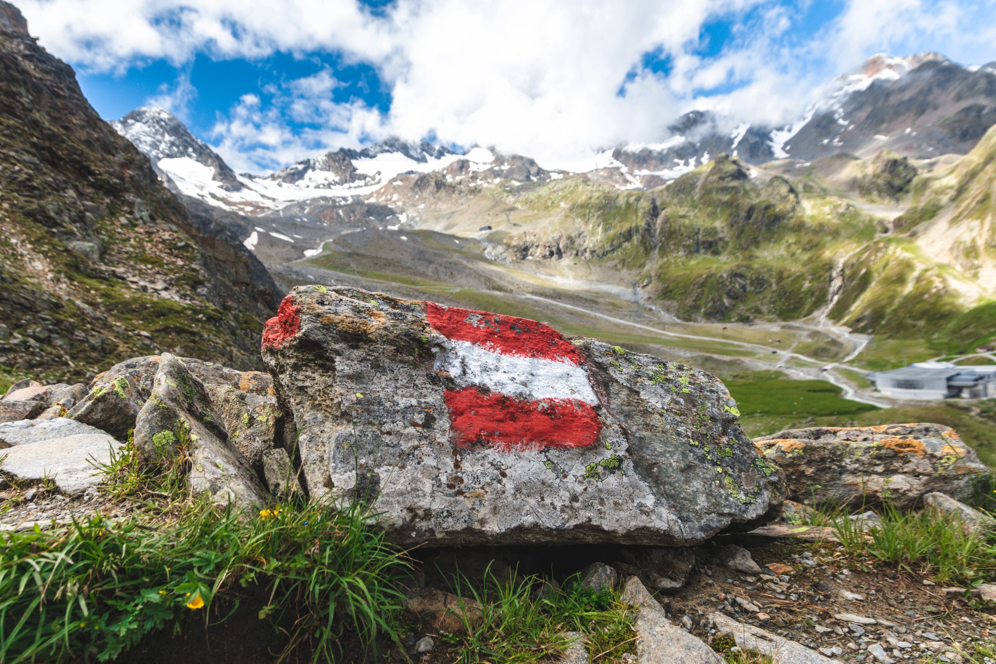Sentier de randonnée alpine en Autriche, marqué par un drapeau autrichien peint sur une roche le long du chemin. Cette roche peinte est située dans la vallée de Stubai, dans le Tyrol autrichien.