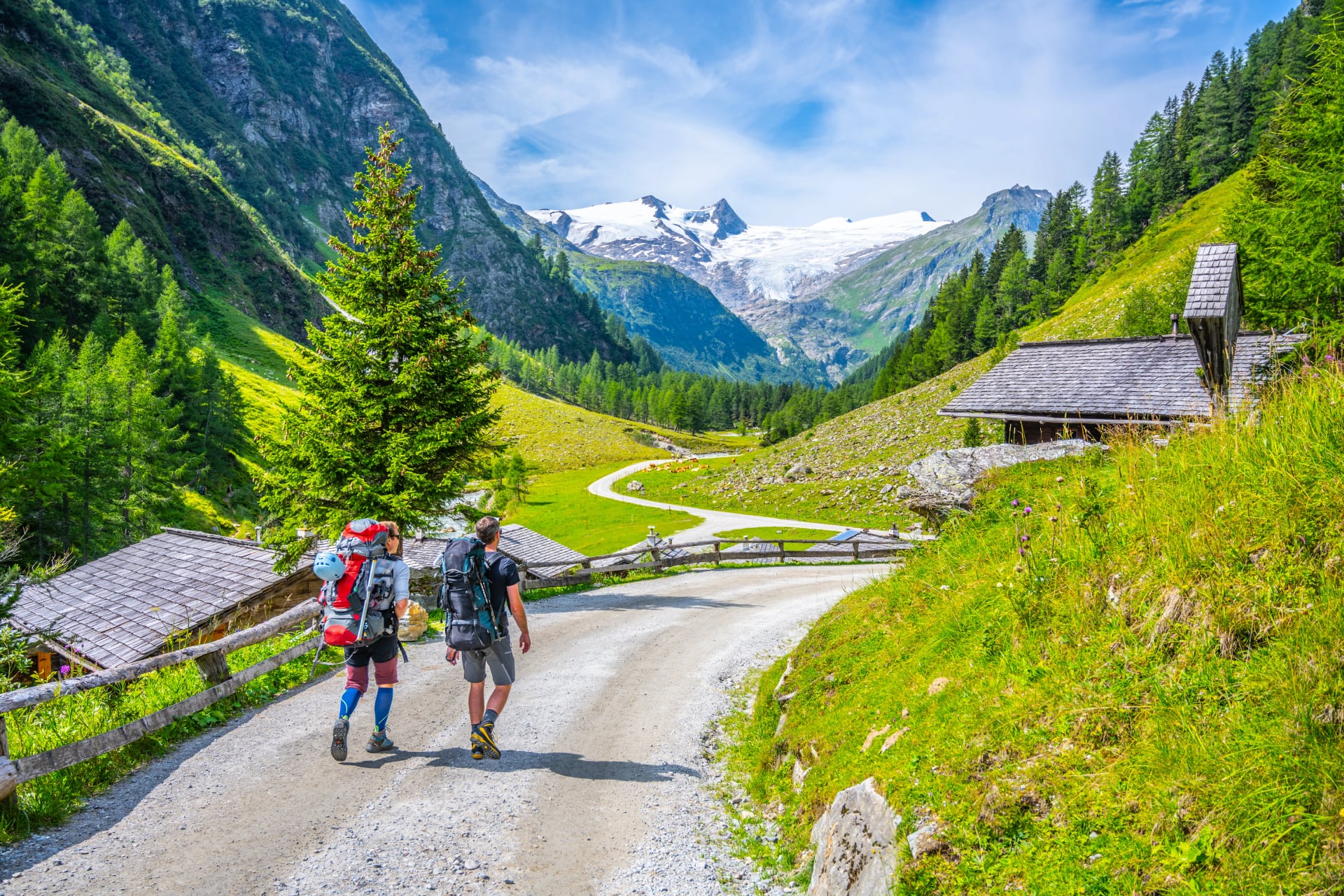 To backpackere vandrer på landevejen mod høje bjerge. Grossvenediger i Hohe Tauern Nationalpark, Østrigs Alper