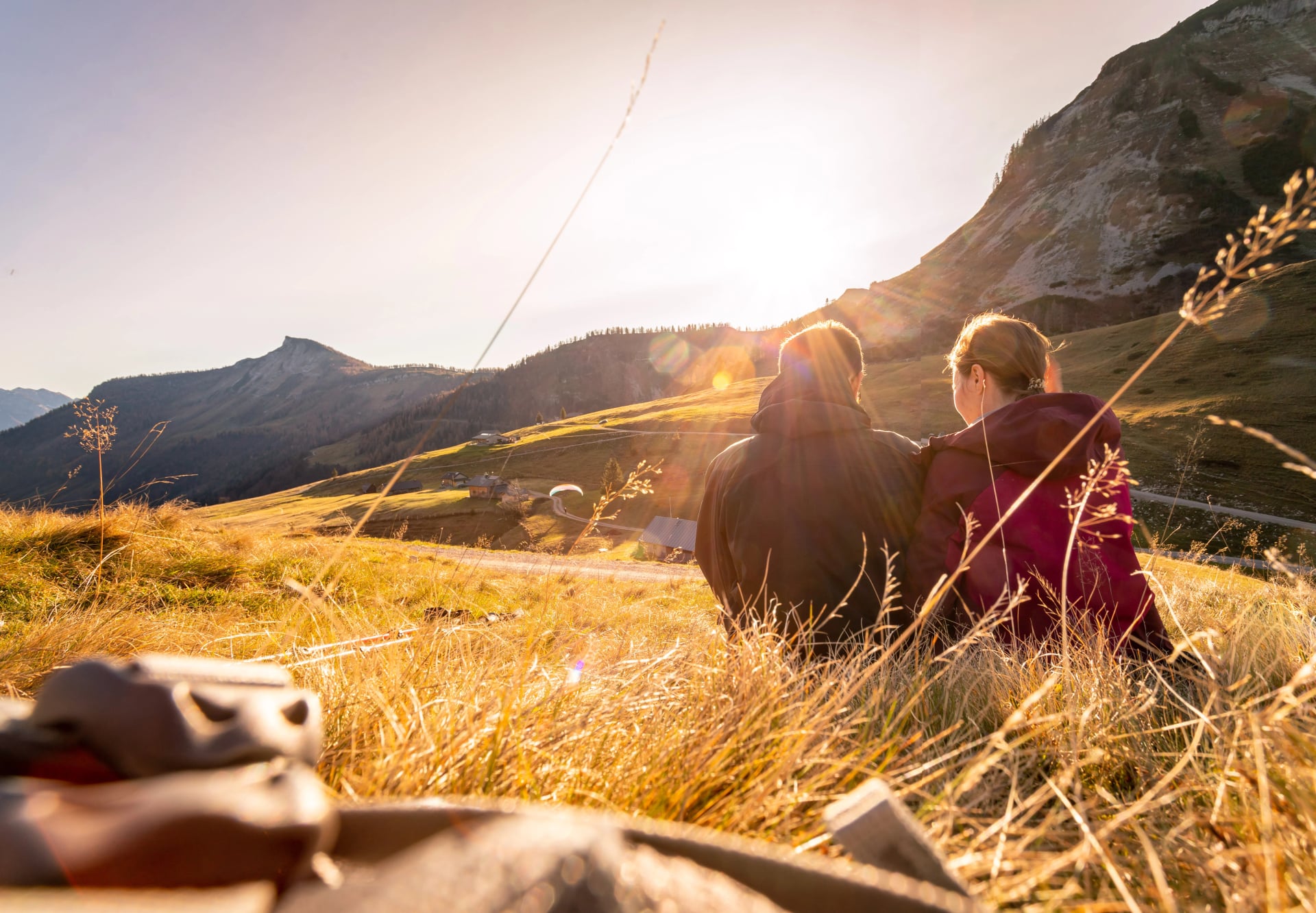 Liebendes Paar genießt den Sonnenuntergang in den Bergen, sitzt auf dem Boden. Warme Farben, Alpen, Österreich