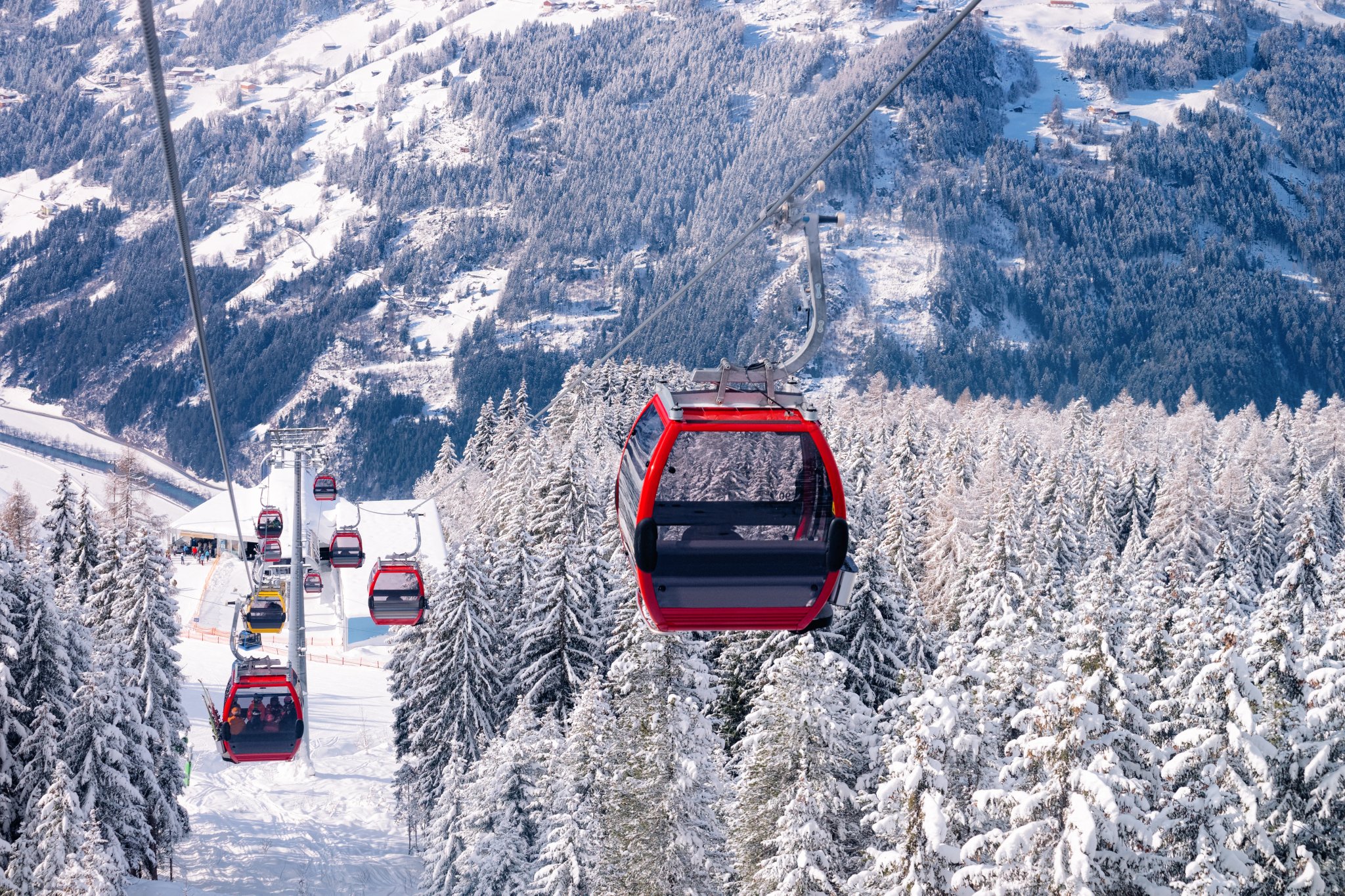 Téléphériques rouges de la station de ski Zillertal Arena en Tyrol à Mayrhofen en Autriche dans les Alpes d'hiver. Télésièges dans les montagnes alpines avec de la neige blanche et un ciel bleu. Plaisir de ski sur les pentes enneigées autrichiennes.