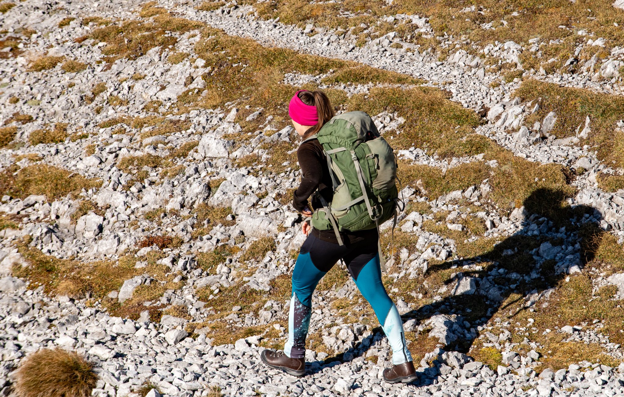 Jeune femme en chaussures de randonnée avec un grand sac à dos vert trekking dans les montagnes rocheuses, Ambiance automnale dans la chaîne de montagnes Hochschwab, Styrie, Alpes autrichiennes, Europe. Liberté et nature sauvage. Pentes dorées.