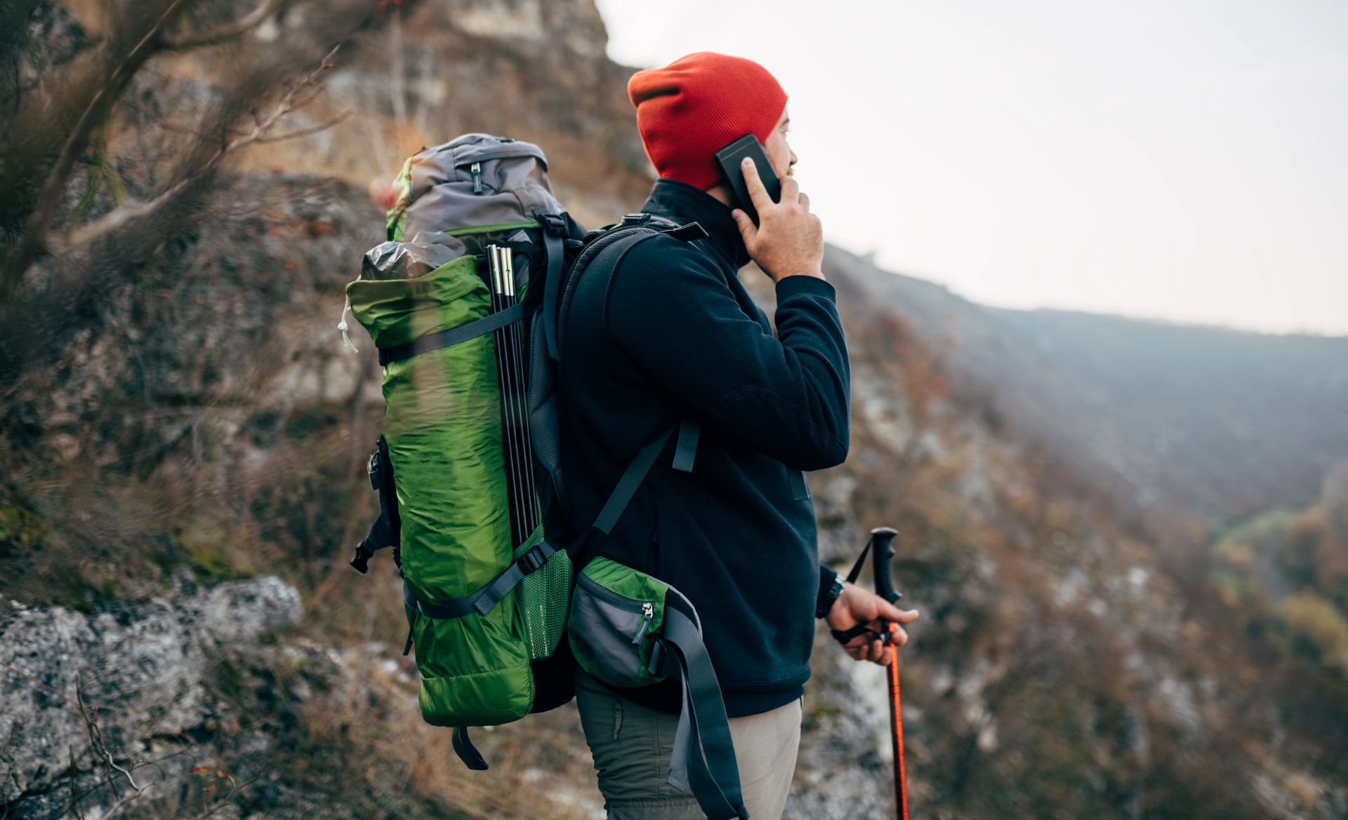 Portrait de profil d'un jeune explorateur en randonnée dans les montagnes, ayant un appel avec son ami. Un homme voyageur parlant avec sa famille en utilisant son smartphone pendant la randonnée en montagne. Voyage, personnes