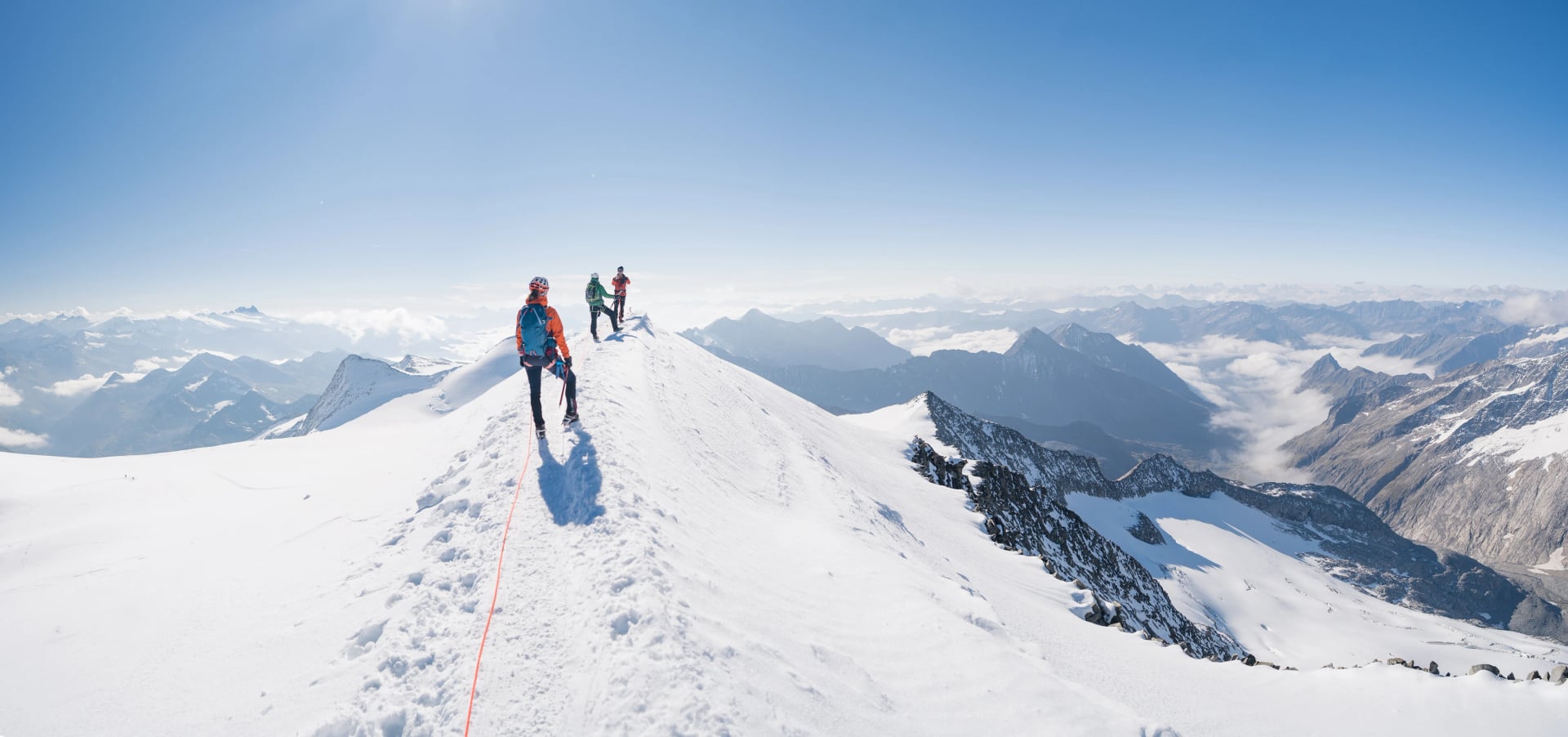 Bergsteigerteam auf einem Weg durch einen gefährlichen Gletscher und Lawinen in den österreichischen Alpen. Epischer Moment nahe dem Gipfel des Großvenediger-Gletschers, als die Wolken für einen Moment verschwinden.