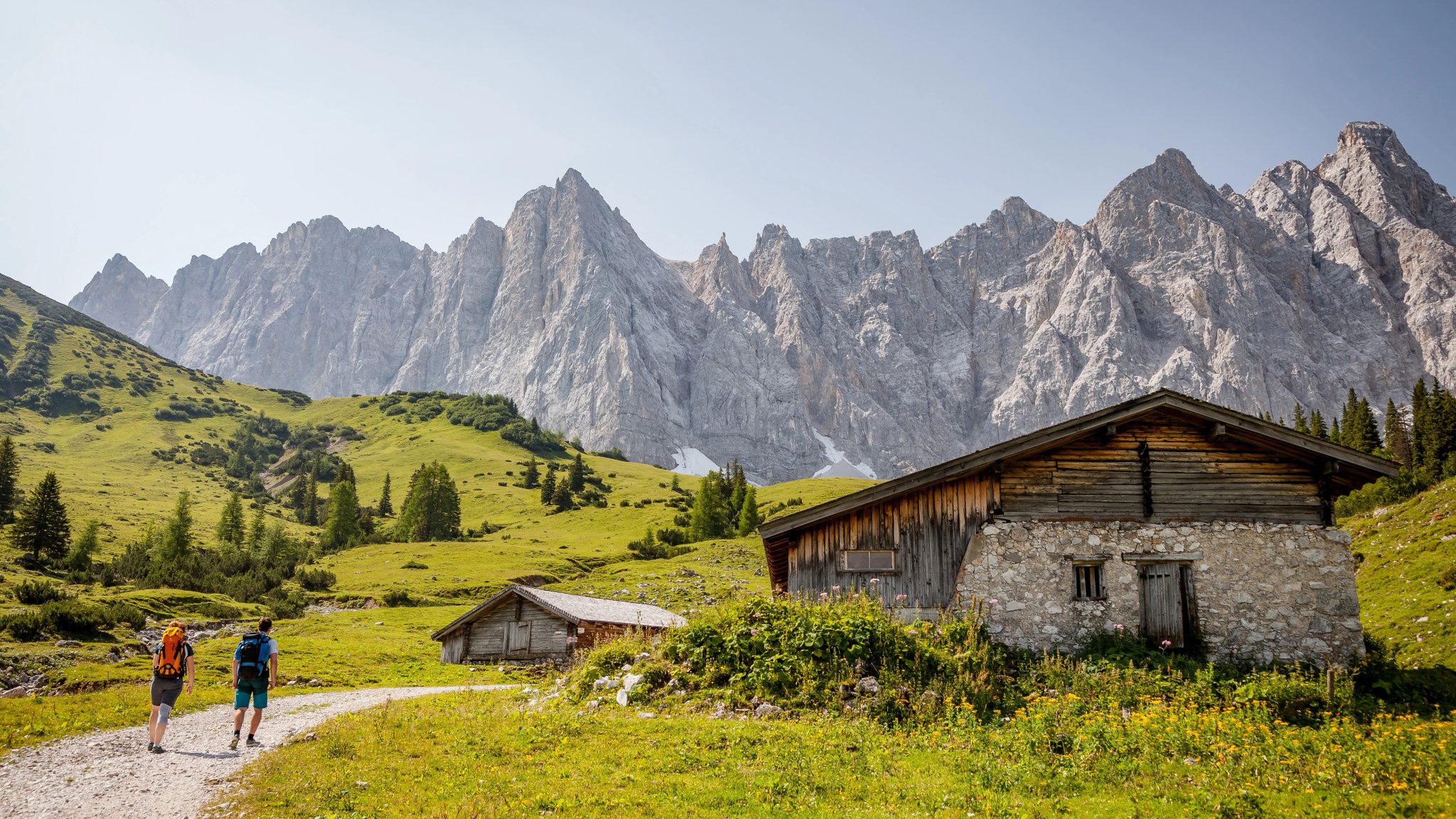 Wandern im Alpenpark Karwendel, Österreich, mit Berglandschaft im Hintergrund, Rucksacktouristen und Hütte