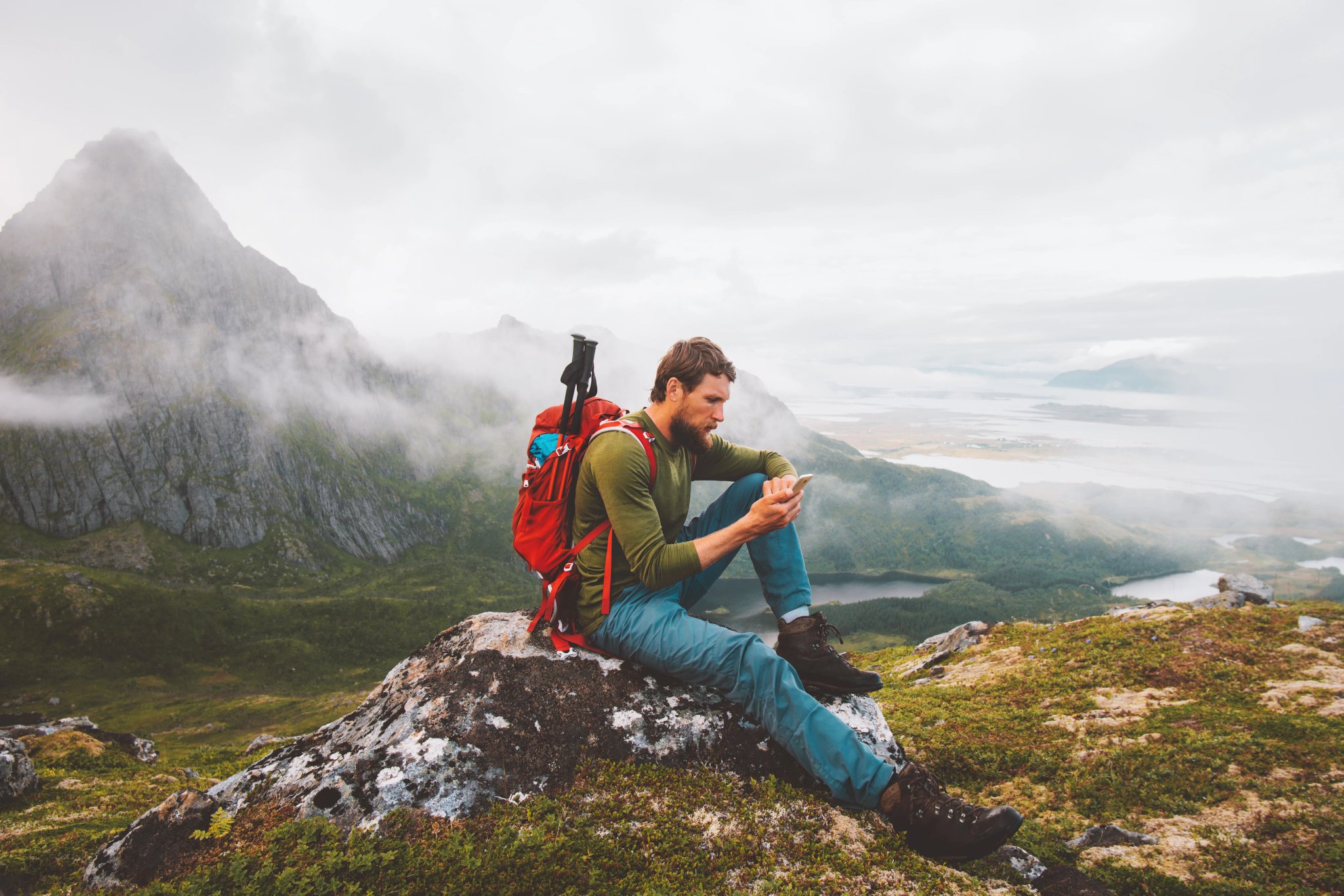 Mann mit Smartphone beim Wandern in den Bergen, Reiseblogger, Influencer, Lebensstil, Abenteuer, Sommerurlaub, Outdoor in Norwegen