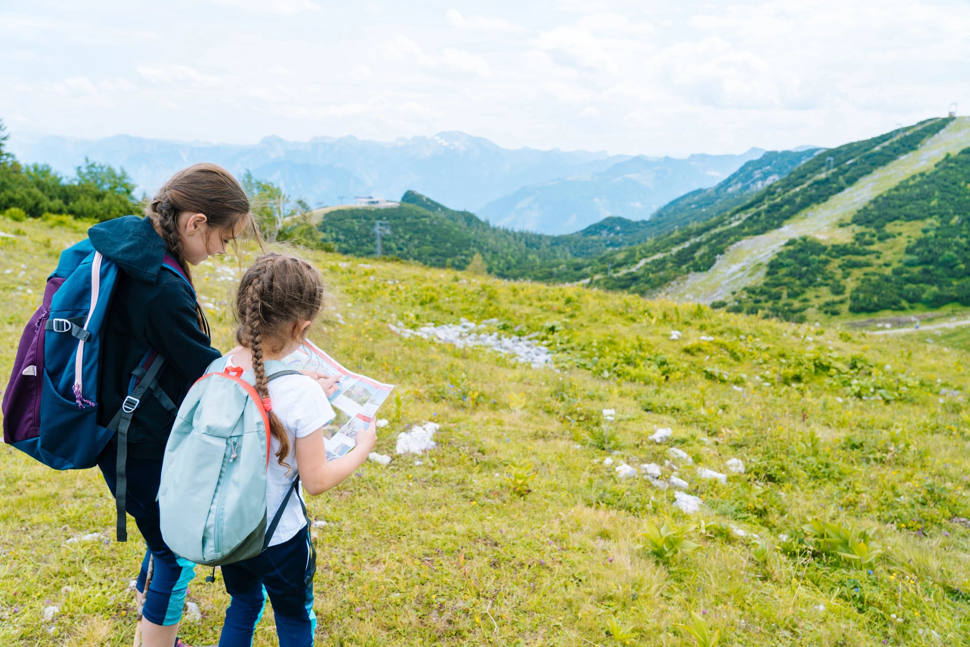 Bambini in escursione in una bella giornata estiva nelle montagne alpine in Austria, riposando su una roccia. I bambini guardano la mappa delle cime montuose nella valle. Vacanza attiva in famiglia, svago con i bambini. Divertimento all'aperto e attività sana