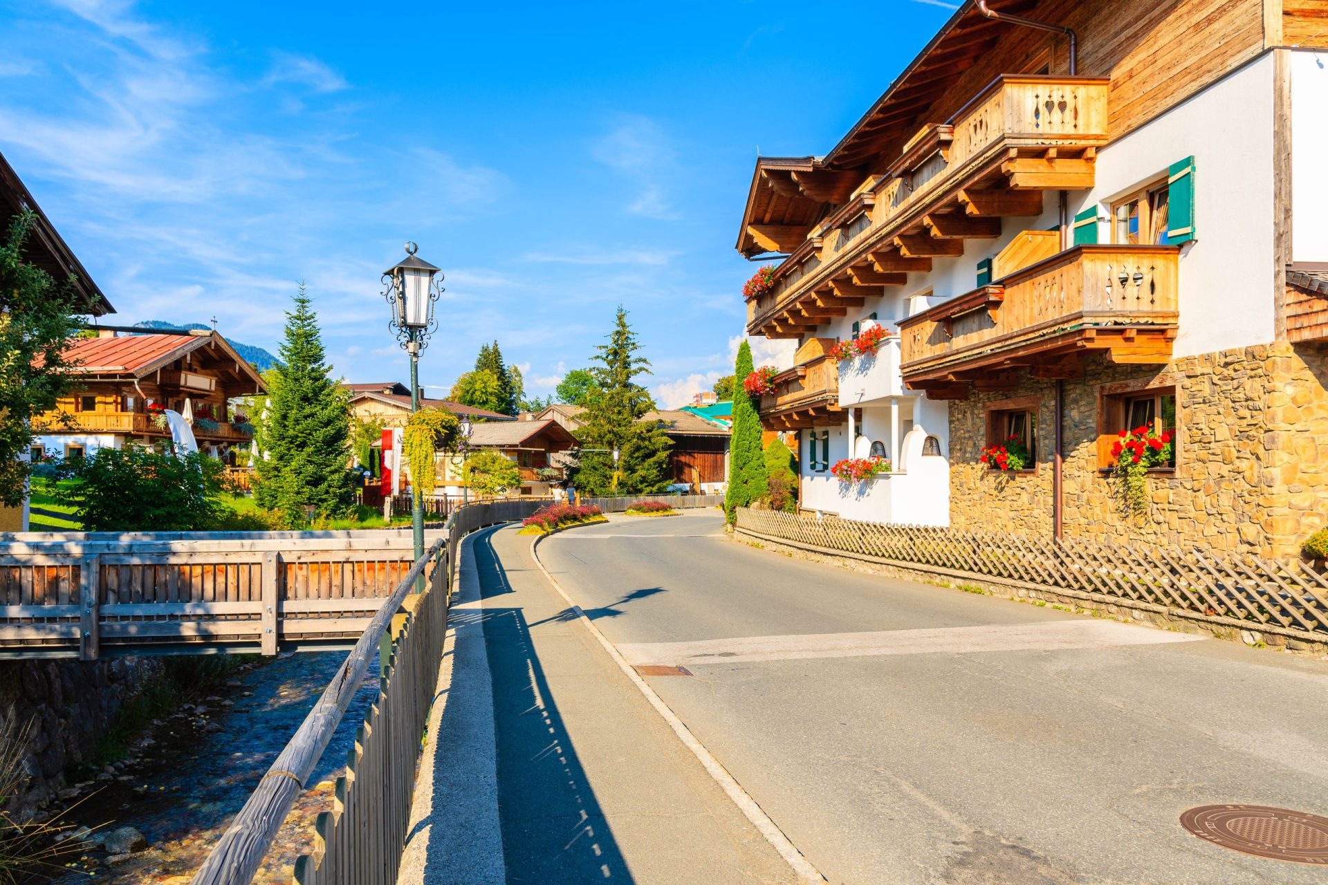 Traditionelle Alpenhäuser auf der Straße im Dorf Going am Wilden Kaiser an einem schönen sonnigen Sommertag, Tirol, Österreich