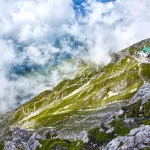 Paisaje de montaña con bosque y cielo azul en los Alpes austriacos.